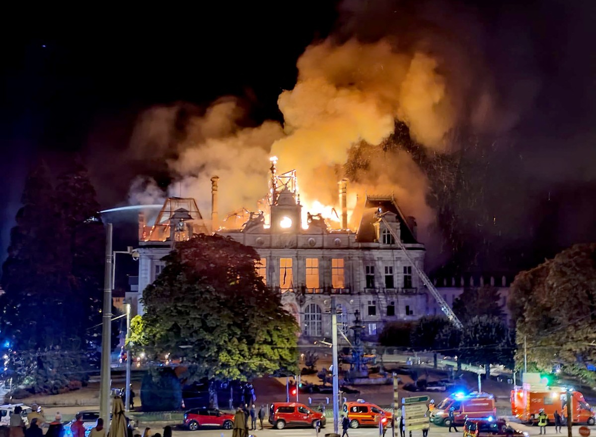 the elegant town hall building well ablaze, flames shooting from the roof into the dark night sky